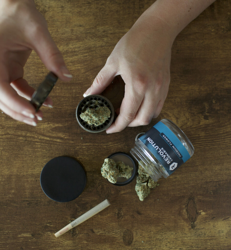 An overhead view of cannabis flower, a jar and a joint on a table.