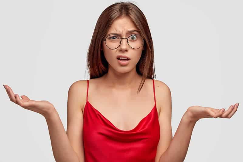 headshot of a confused young woman in a red top.