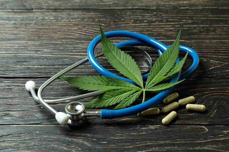 medicinal cannabis and stethoscope on rustic wooden background