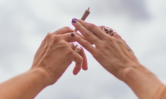 A pair of hands passing an unlit joint between them.